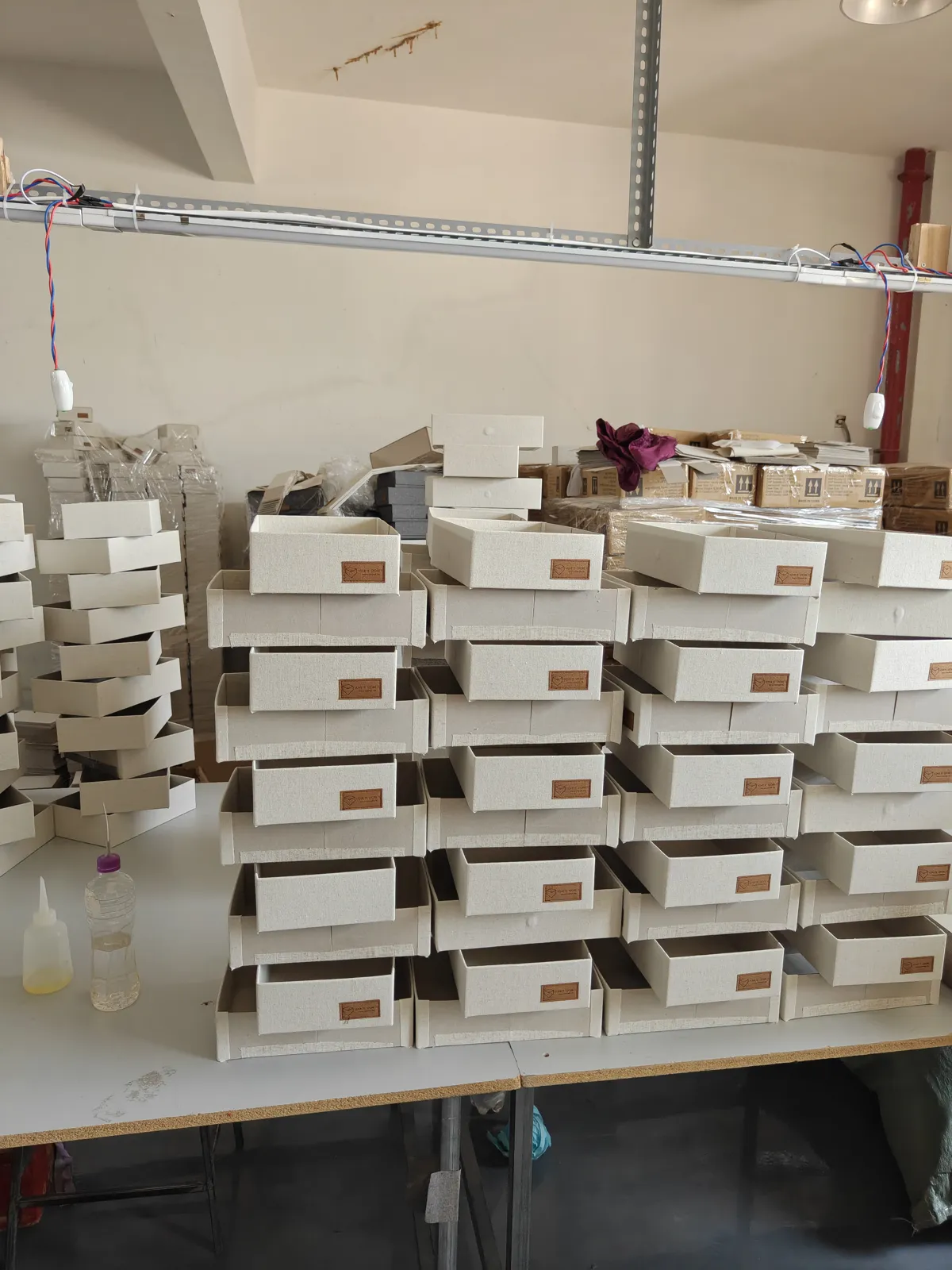 Linen jewelry trays stacked on a factory workbench before the leather tab is added